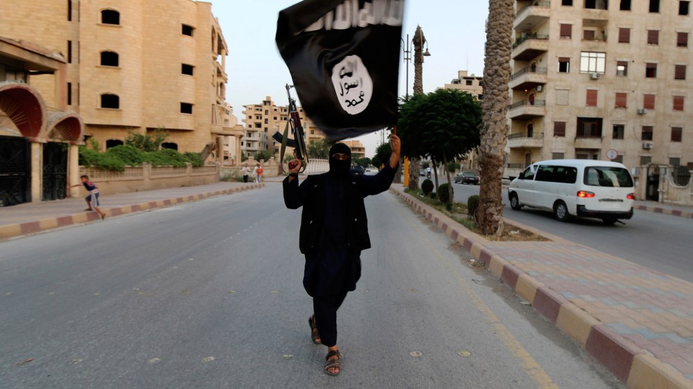 A member loyal to the ISIL waves an ISIL flag in Raqqa