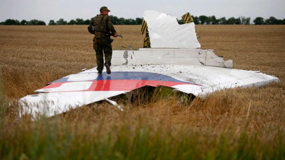 An armed pro-Russian separatist stands on part of the wreckage of the Malaysia Airlines Boeing 777 plane after it crashed near the settlement of Grabovo in the Donetsk region, July 17, 2014.