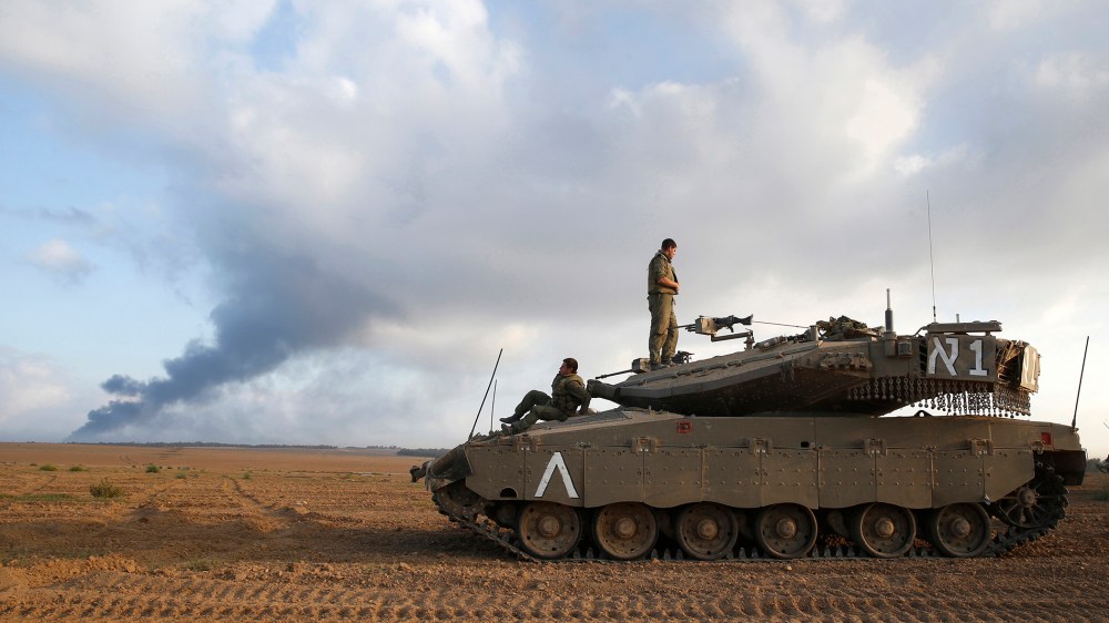 Israeli soldiers are seen atop a tank outside the central Gaza Strip