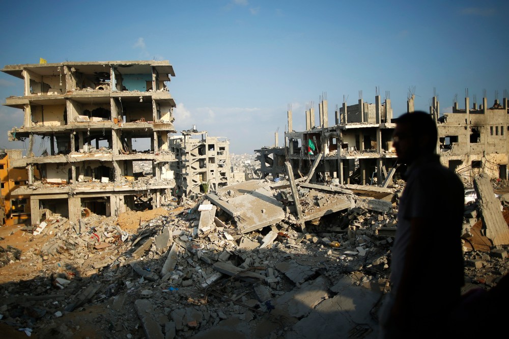 A Palestinian man stands atop the rubble of his house as he looks at the ruins of neighboring houses that witnesses said were destroyed or damaged during the 50-day war between the Hamas militant movement and Israel, in the east of Gaza City.