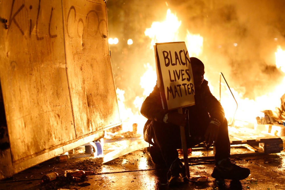 A demonstrator sits in front of a street fire during a demonstration following the grand jury decision in the Ferguson, Mo. shooting of Michael Brown, in Oakland, Calif. Nov. 25, 2014. (Photo by Stephen Lam/Reuters)