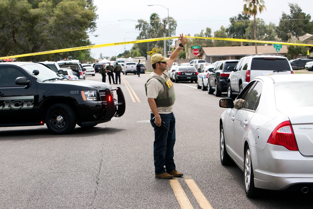 An FBI agent lifts police tape at one of the scenes of a multiple location shooting that has injured at least four people in Mesa, Arizona on March 18, 2015. (Photo by Deanna Dent/Reuters)