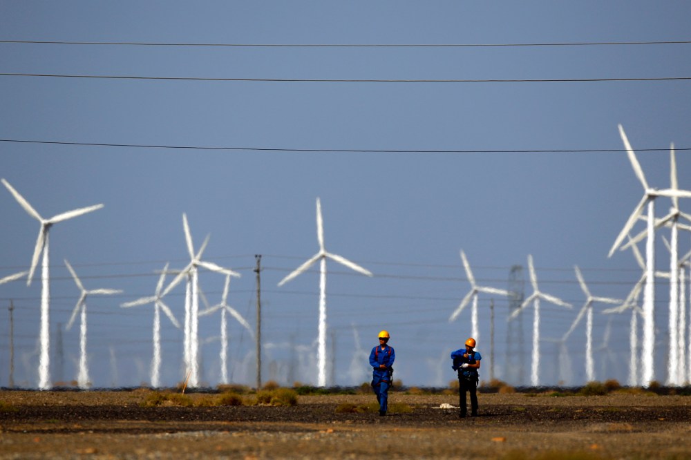 Workers walk near wind turbines for generating electricity, at a wind farm in Guazhou, 950km (590 miles) northwest of Lanzhou, Gansu Province, Sep. 15, 2013. (Photo by Carlos Barria/Reuters)