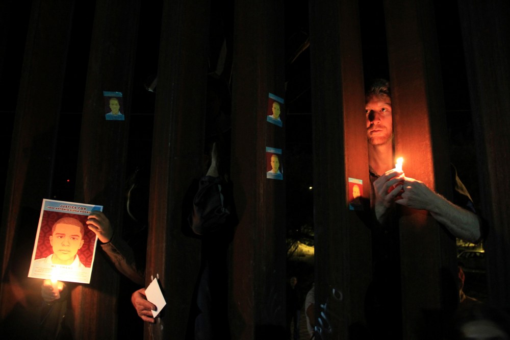 Activists hold candles and pictures of late Mexican youth Jose Antonio Elena Rodriguez through the border fence between Mexico and the U.S. in Nogales, Oct. 10, 2013. (Photo by Stringer/Reuters)