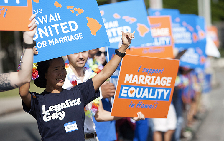 Keri Bias (L) holds a sign in support of same sex marriage in front of the Hawaii State Capital in Honolulu October 28, 2013.