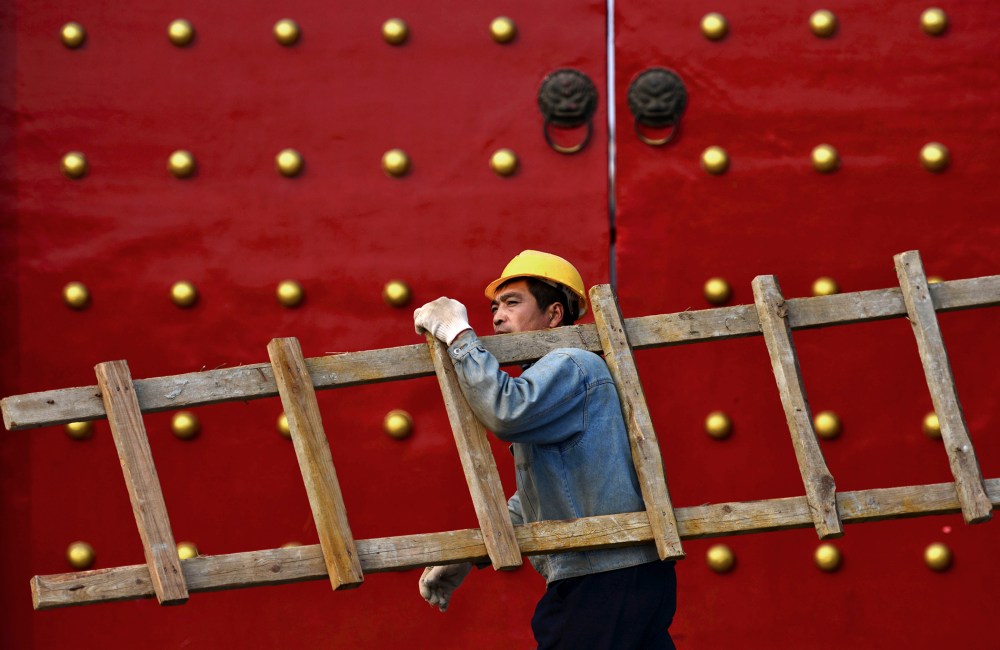 A worker carrying a ladder walks past a palace used by ancient emperors in Shenyang