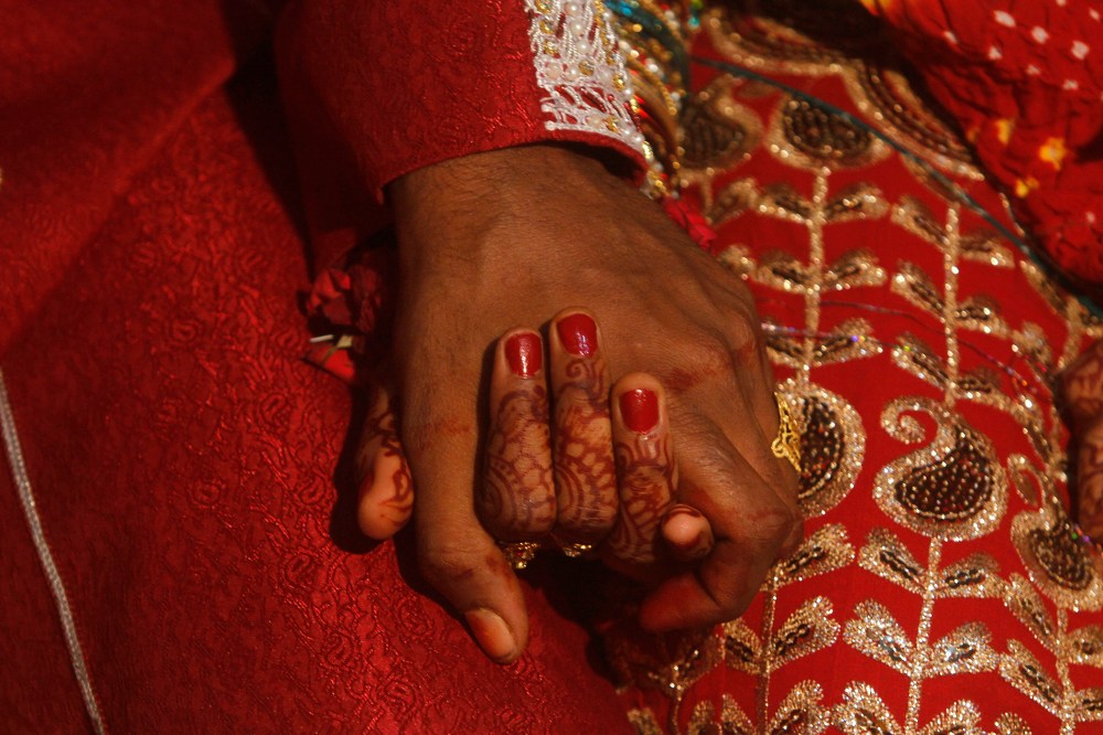 A bride and groom hold hands as they sit together during a mass marriage ceremony held in Karachi, Nov. 30, 2013. (Photo by Athar Hussain/Reuters)
