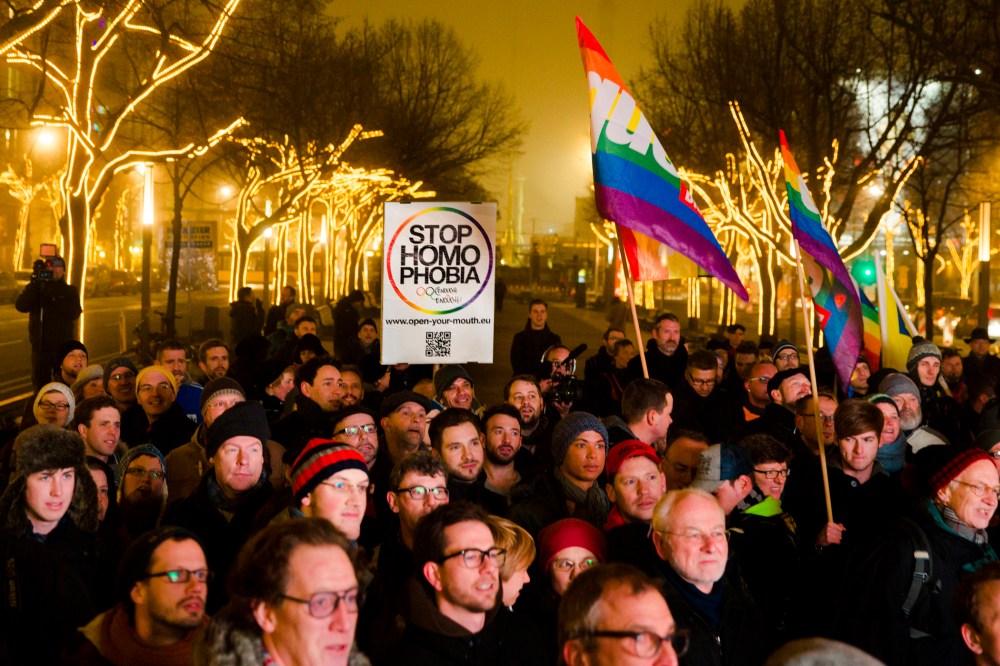 People hold a placard and rainbow flags as they call on the Russian authorities to lift anti-gay laws ahead of the Sochi 2014 Olympics during a protest outside the Russian embassy in Berlin, Dec. 12, 2013.