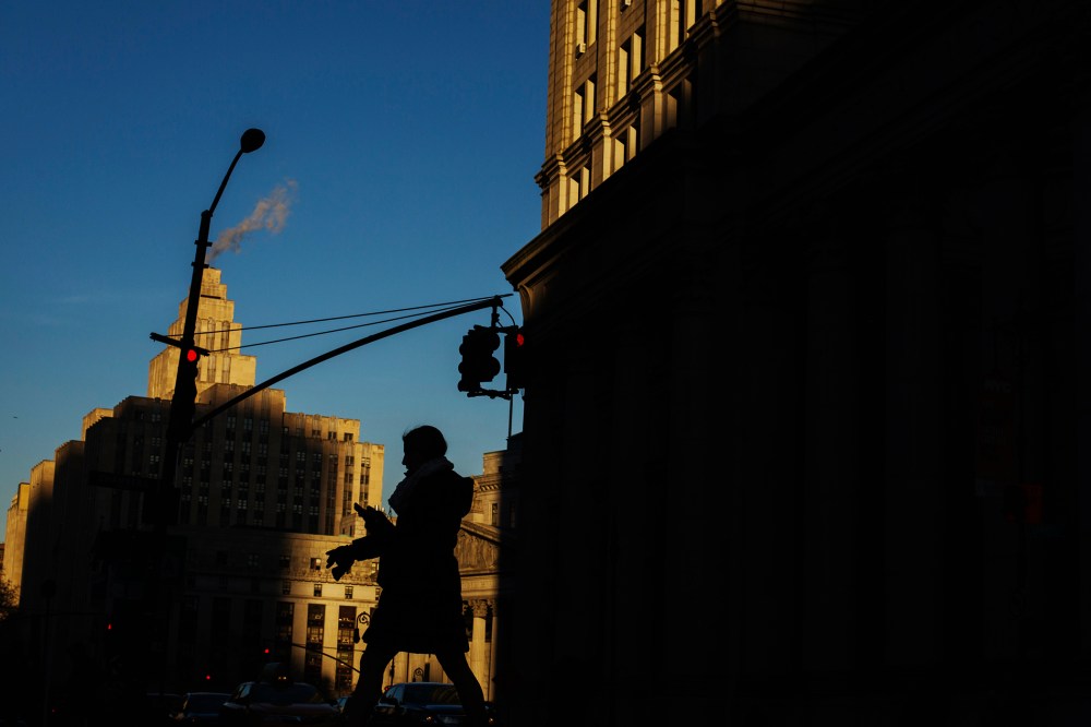 A woman crosses the street as the setting sun illuminates buildings behind her in New York, N.Y. (Photo by Lucas Jackson/Reuters)