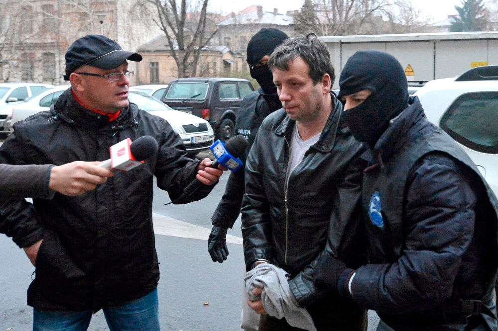 Marcel Lazar Lehel, 40, is escorted by masked policemen in Bucharest, after being arrested in Arad, 550 km (337 miles) west of Bucharest, Jan.22, 2014. (Photo by Silviu Matei/Mediafax/Reuters)