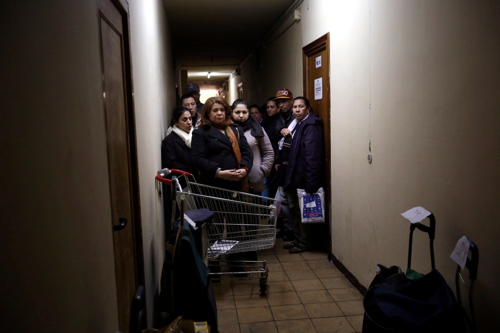 Food bank recipients wait for their cart numbers to be called out to pick up their donated food on distribution day at Madrid's Tetuan food bank in Madrid, Spain on Dec. 10, 2013.