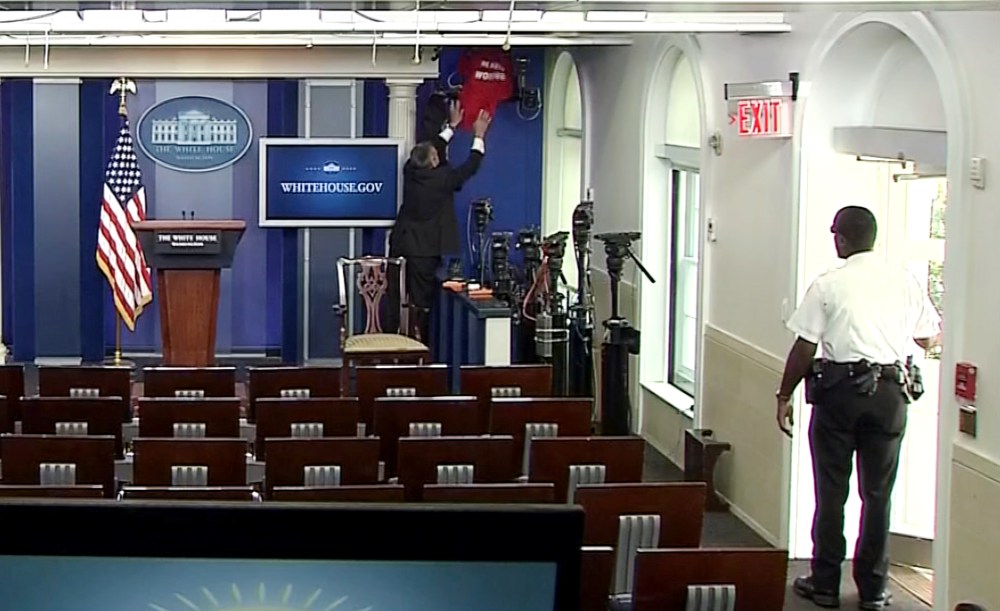 An official covers a network television camera with a shirt after the room was cleared due to a bomb threat during a briefing by White House Press Secretary John Earnest at the White House, June 9, 2015. (Photo by Pool/Reuters)