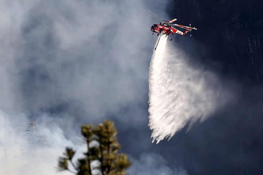 A helicopter makes a water drop on a wildfire near Jenks Lake in the San Bernardino National Forest, Calif., June 18, 2015. (Photo by Lucy Nicholson/Reuters)