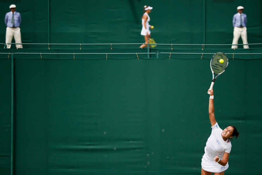 Zarina Diyas of Kazakhstan (foreground) serves during her match against Flavia Pennetta of Italy as Vitalia Diatchenko of Russia looks on during her match against Anna-Lena Friedsam of Germany at the Wimbledon Tennis Championships in London, June 29, 2015