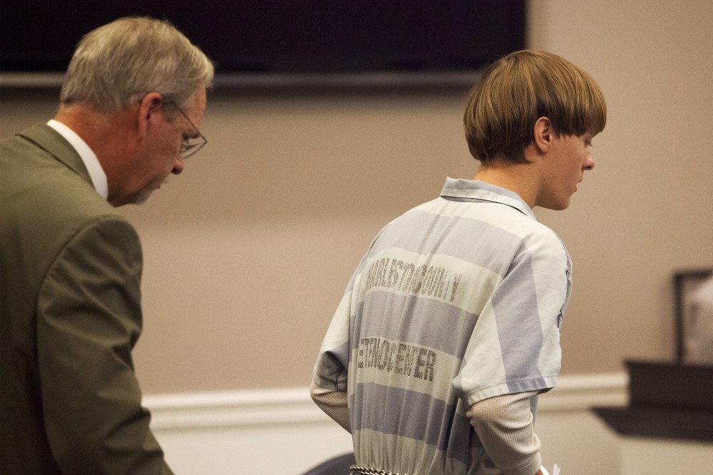 Dylann Roof (R), the 21-year-old man charged with murdering nine worshippers at a historic black church in Charleston last month, is helped to his chair by chief public defender Ashley Pennington during a hearing at the Judicial Center in Charleston
