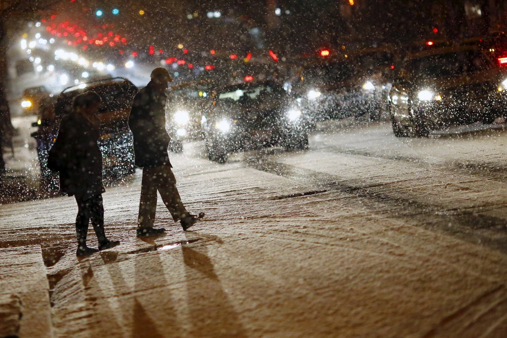 People cross a street as it snows in Washington, Jan. 20, 2016. (Photo by Carlos Barria/Reuters)