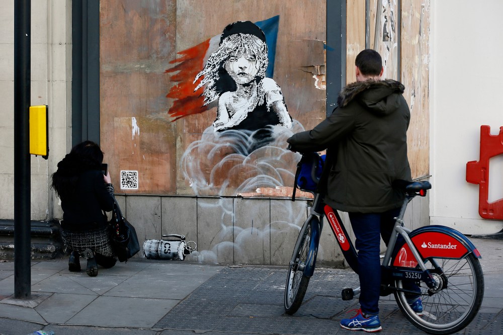People photograph a new graffiti mural attributed to Banksy, opposite the French embassy in London, Jan. 25, 2016. (Photo by Stefan Wermuth/Reuters)