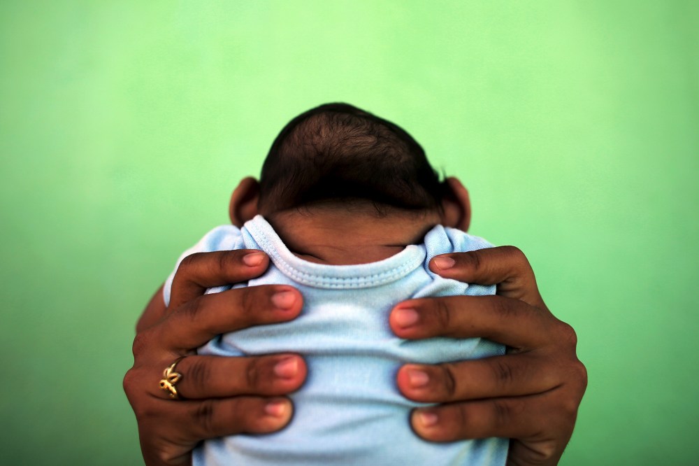 Jackeline, 26, holds her son who is 4-months old and born with microcephaly, in front of their house in Olinda, near Recife, Brazil, Feb. 11, 2016. (Photo by Nacho Doce/Reuters)