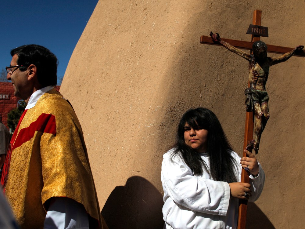 Girl carries crucifix out of the San Francisco de Asis Catholic Church after Easter Mass in Ranchos de Taos