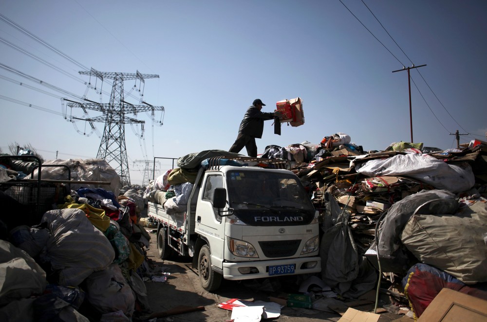 A worker unloads waste at the Xiejiacun waste collection market in the Changping district of Beijing on April 8, 2013.
