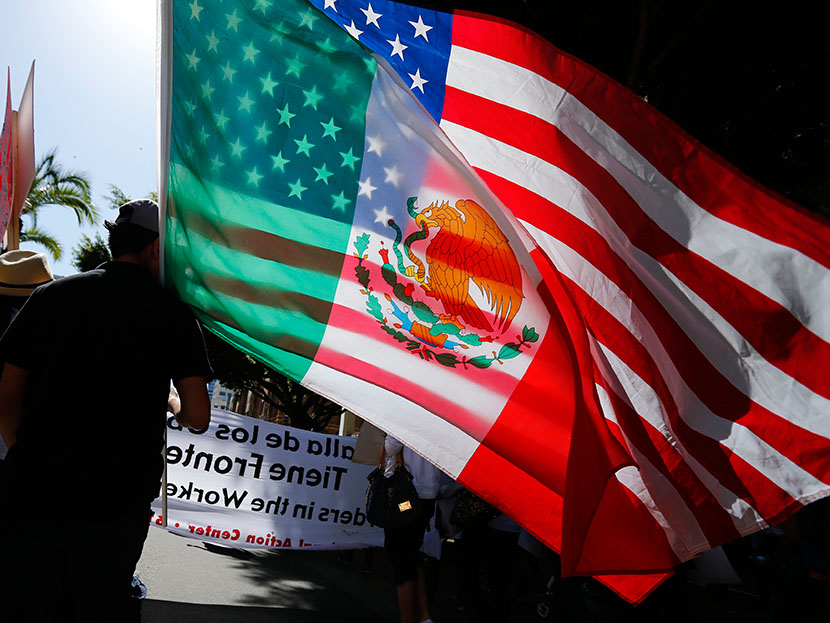 A young man carries national flags of the U.S. and Mexico through the streets during a May Day march, May 1, 2013, in San Diego, Calif.