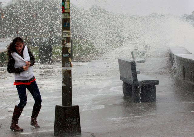 A woman reacts to waves crashing over a seawall in Narragansett, R.I., Monday, Oct. 29, 2012. Hurricane Sandy continued on its path Monday, as the storm forced the shutdown of mass transit, schools and financial markets, sending coastal residents...