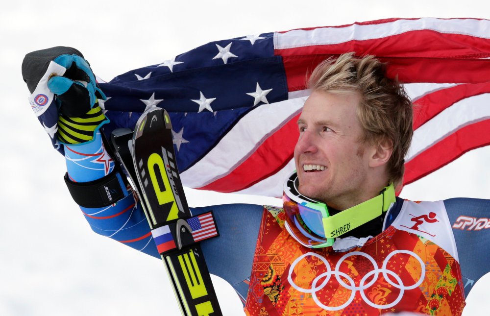 Men's giant slalom gold medalist Ted Ligety of the United States poses for photographers with the American flag on the podium at the Sochi 2014 Winter Olympics, Feb. 19, 2014, in Krasnaya Polyana, Russia.