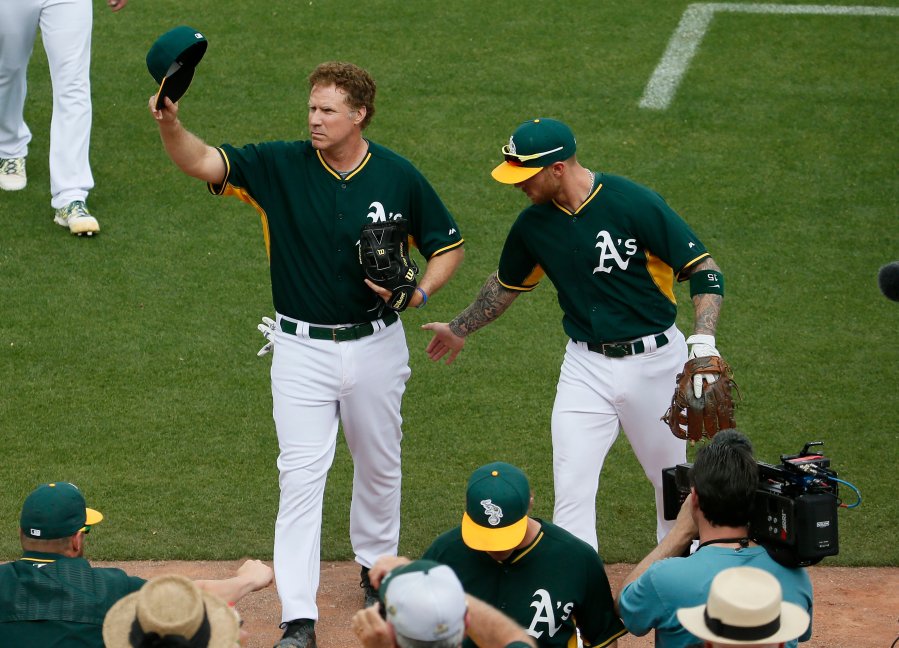 Actor Will Ferrell, left, tips his cap after playing shortstop for the Oakland Athletics during the first inning of a spring training baseball game against the Seattle Mariners, on March 12, 2015, in Mesa, Ariz.