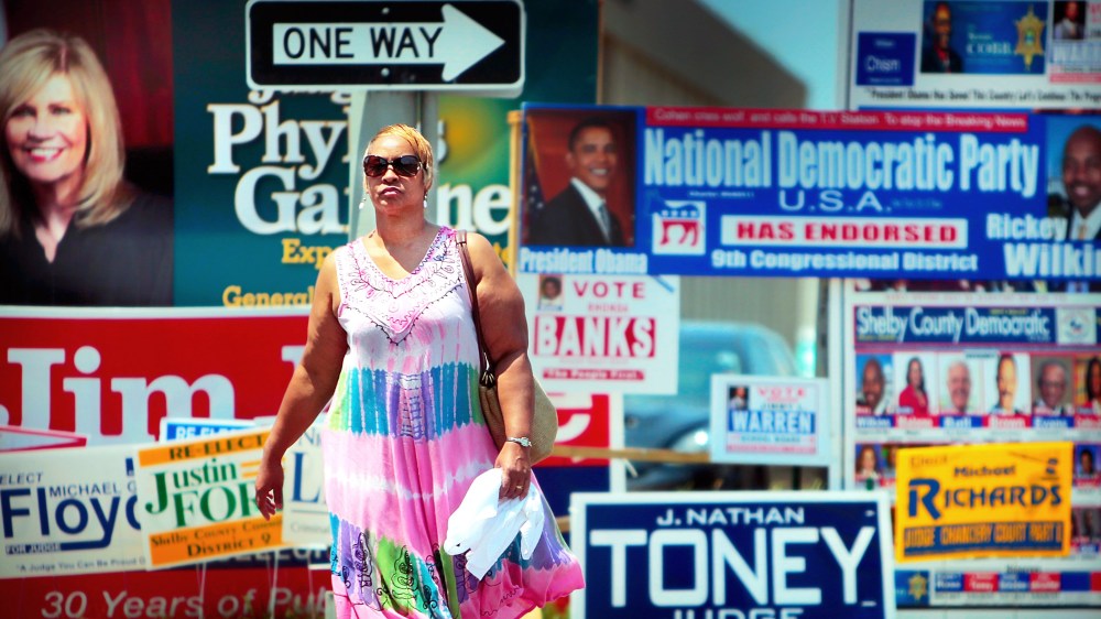 Annette Mallet passes a wall of campaign signs on Poplar Ave. Wednesday, Aug. 6, 2014 near the Shelby County Election Commission Offices in Memphis, Tenn.