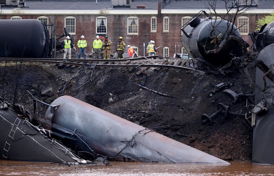Image: Firefighters and rescue personnel work along the tracks where several CSX tanker cars carrying crude oil derailed
