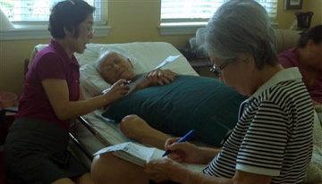 In this Oct. 17, 2012 photo provided by Irene Tanabe, 93-year-old World War II veteran Frank Tanabe, center, gets help from his daughter Barbara Tanabe, left, to fill out his absentee ballot in Honolulu while his wife Setsuko Tanabe sits in the...