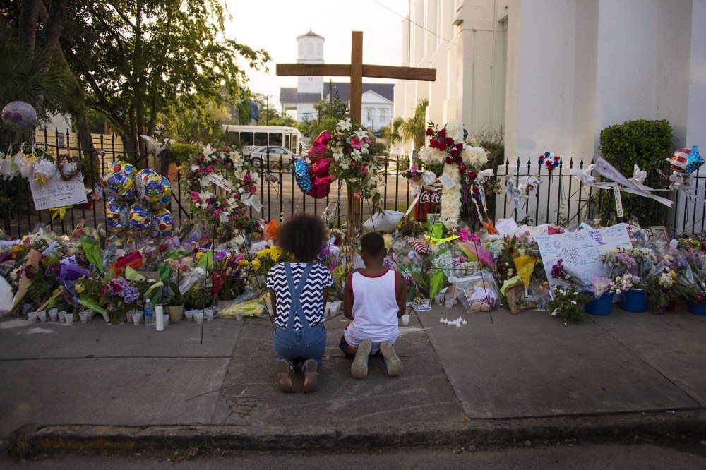 Two children pray near thousands of flowers and cards left in condolence outside Emanuel AME Church in Charleston, S.C., on June 23, 2015. (Photo by Jim Watson/AFP/Getty)