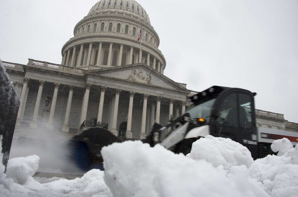 A snow plow passes by pushing away slush outside the U.S. Capitol Building in Washington, D.C., December 10, 2013.
