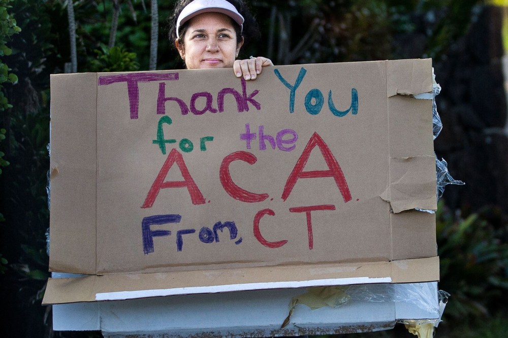 A woman holding a sign in support of the Affordable Care Act is seen as President Barack Obama's motorcade returns to his vacation compound from the gym at Marine Corps Base Hawaii on December 29, 2013 in Kaneohe Bay, Hawaii.