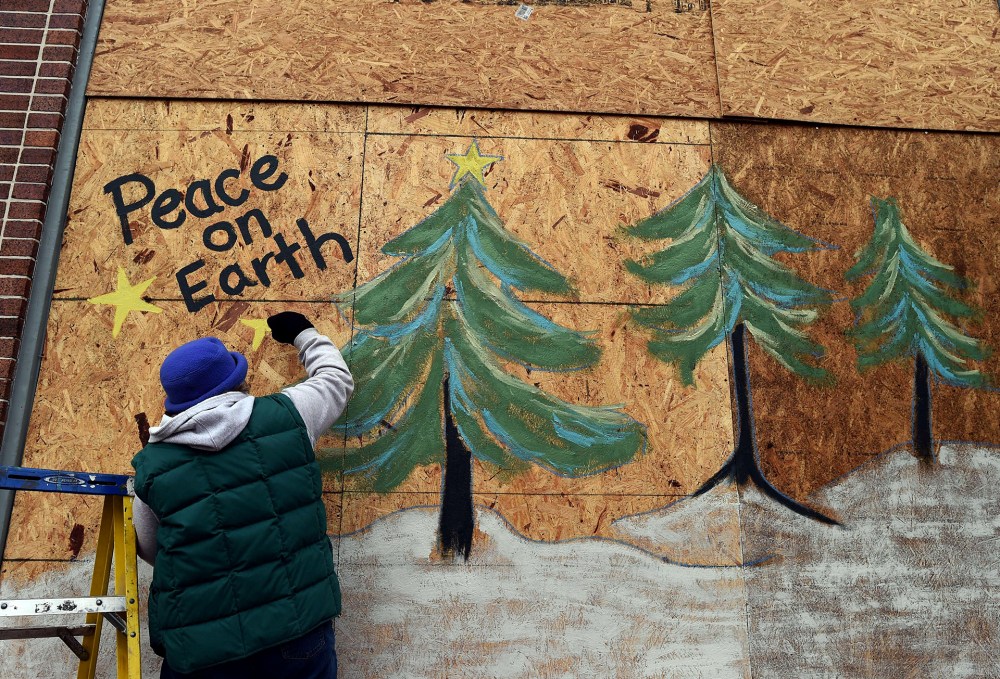 Karen Gold paints on a boarded window of her store in Ferguson, Missouri, on Nov. 26, 2014.