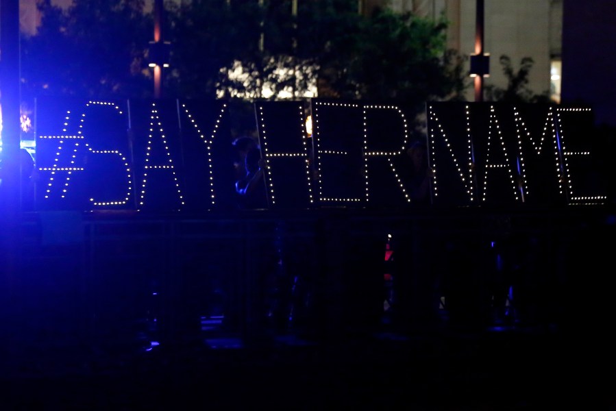 Protestors hold up a lighted sign reading 