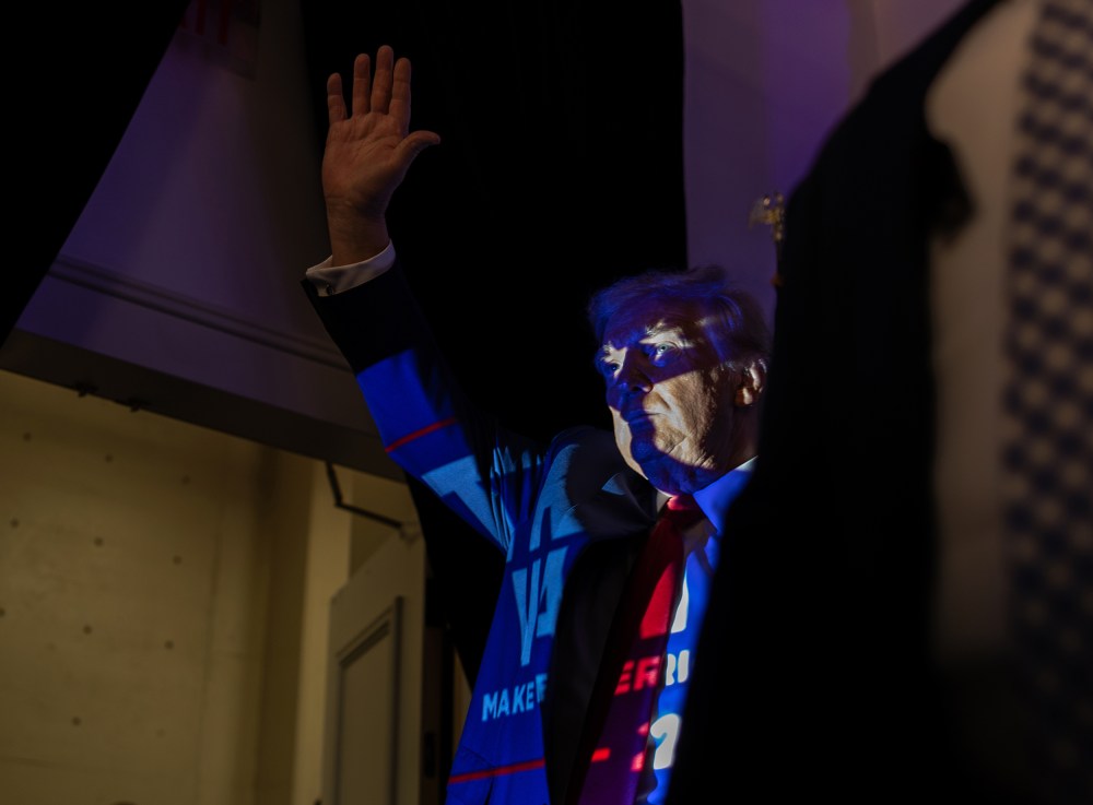 Donald Trump in Charlotte, N.C., with a projection of a Trump 2024 poster casting onto him.