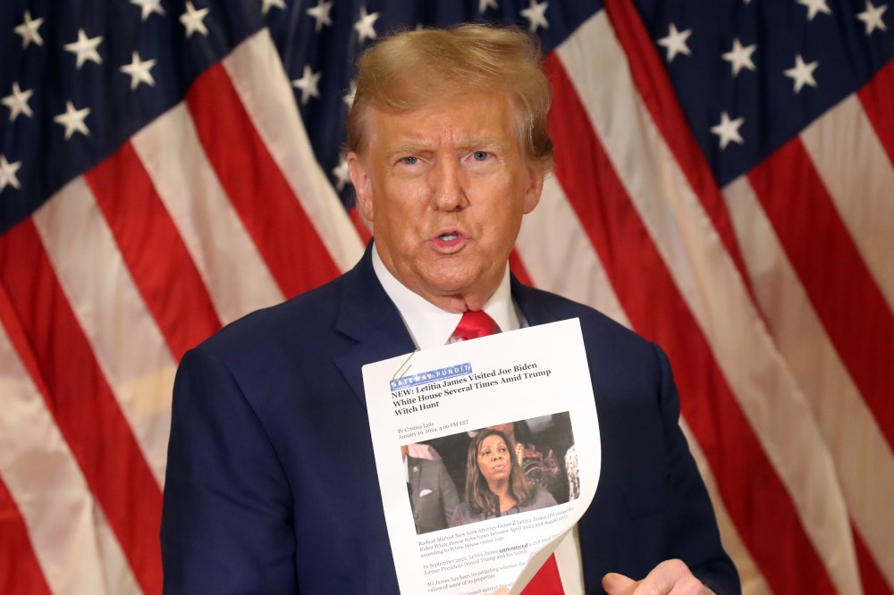 Then former U.S. President Donald Trump holds up a news story about New York Attorney General Letitia James as he speaks to the media at one of his properties at 40 Wall Street following closing arguments at his civil fraud trial on Jan. 11, 2024, in New York City.