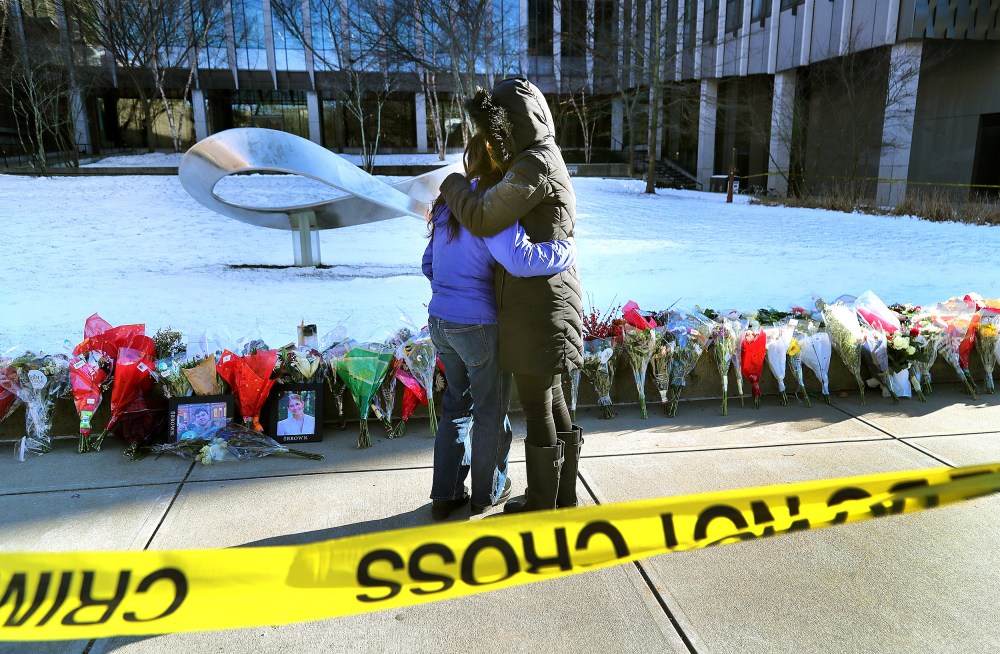 People hug in front of a memorial at Brown University.