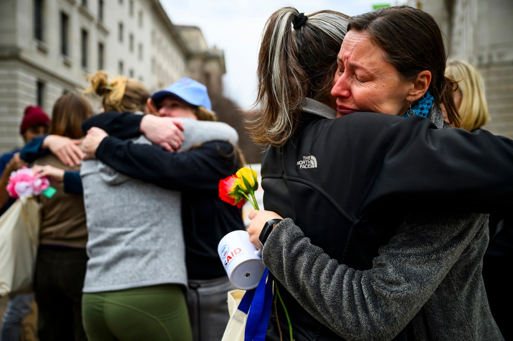 Prarie Summer, a USAID contractor for almost 10 years, right, cries as she embraces a Alexandra Jung after leaving the agency's former offices at the Ronald Reagan Building and International Trade Center.
