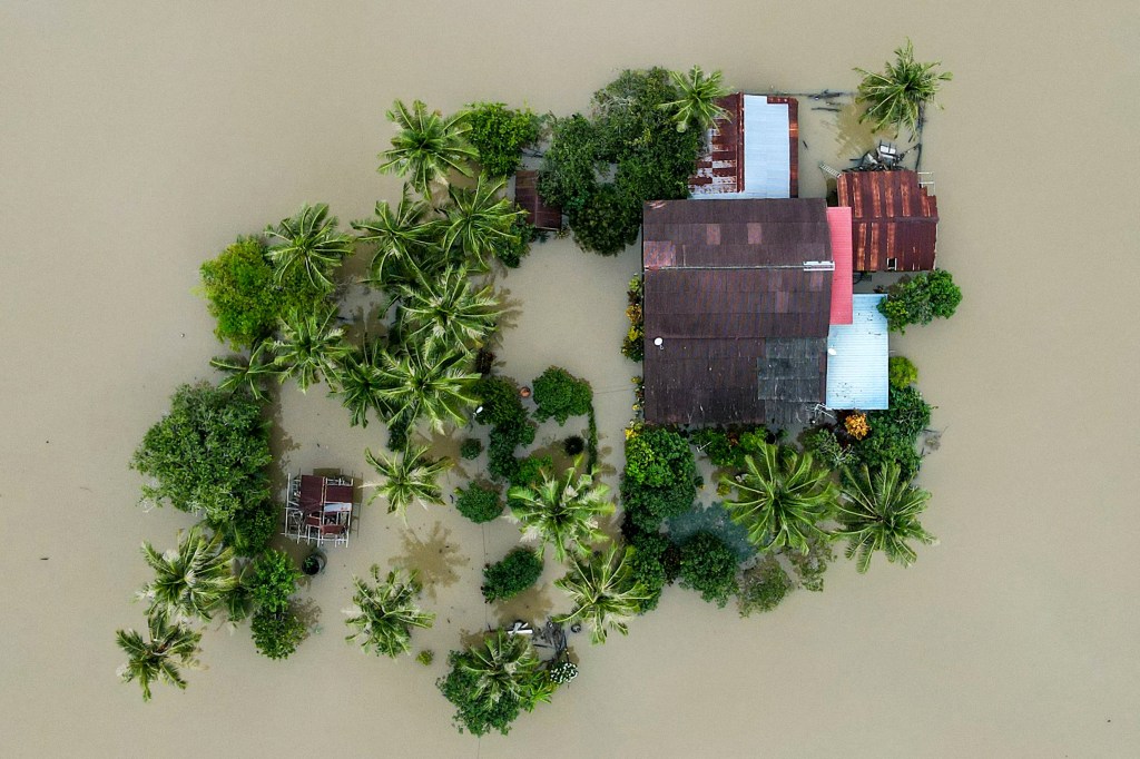 An aerial view of a home surrounded by flood waters.