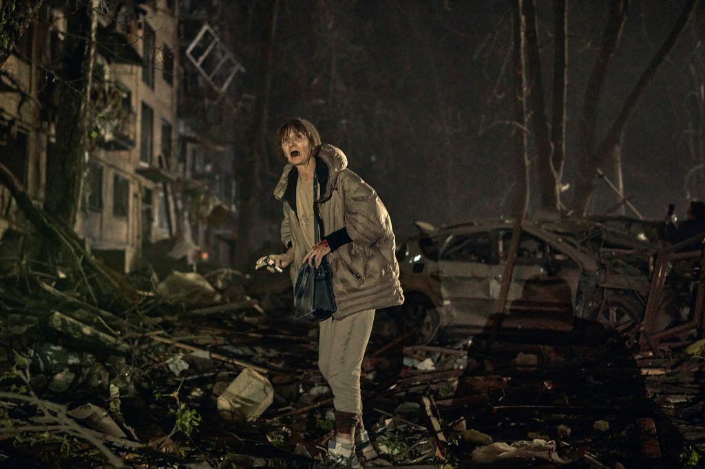 A woman with her mouth agape stands among debris after missile strike on a residential building in Kyiv, Ukraine.