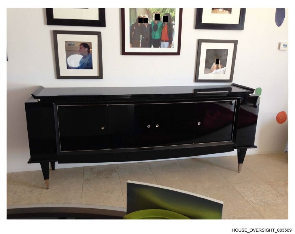 A photo showing a credenza with redacted framed photos above it on a wall