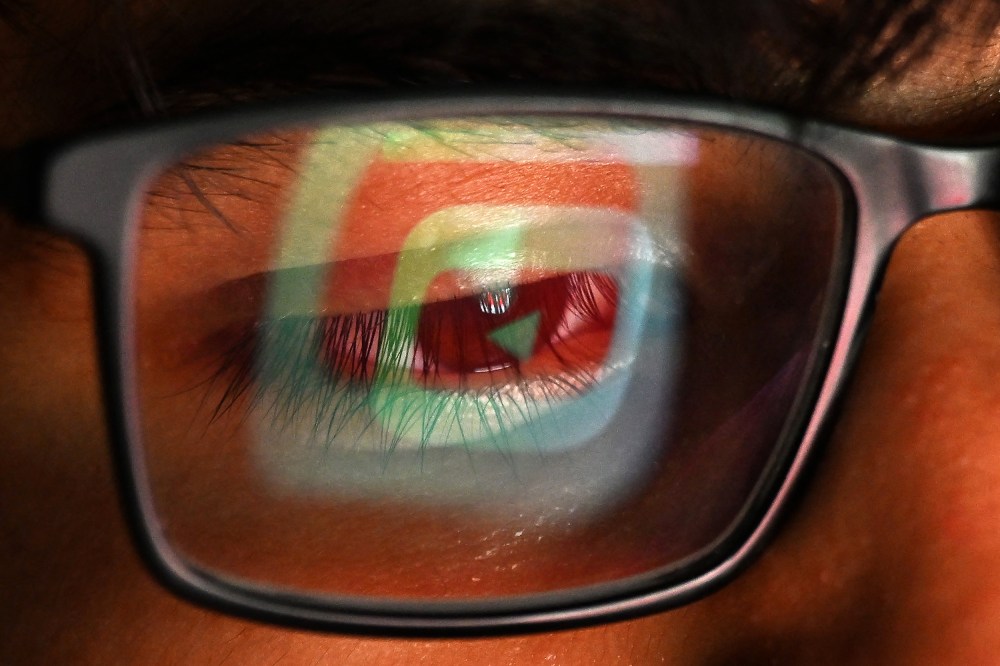 The YouTube logo is reflected in one lens of a person's glasses.