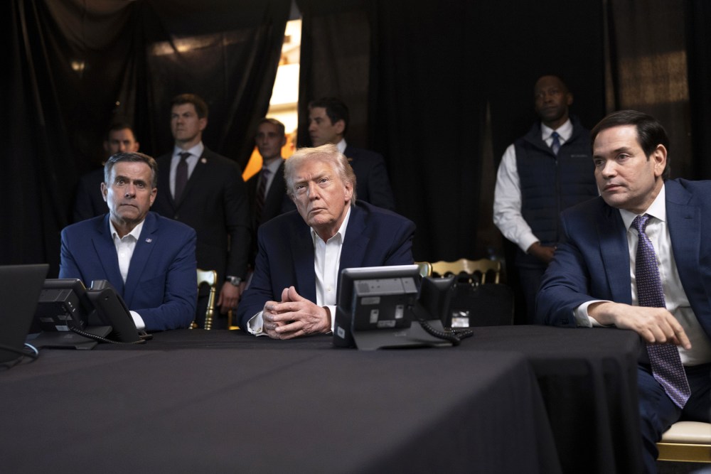 President Donald Trump, center, sits with his hands folded.