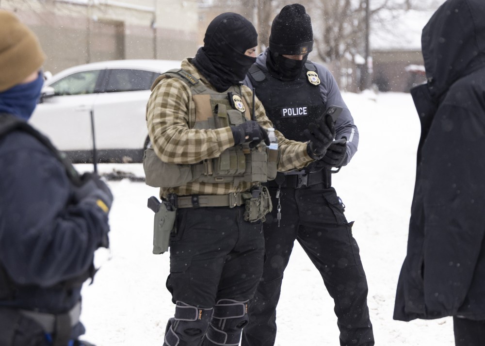 ICE agents check's a man's immigration status on a snowy street in Minnesota.
