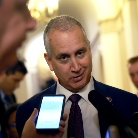 Mario Díaz-Balart looks at the camera as microphones are held to his face.