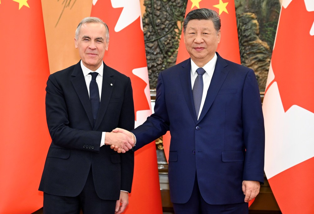 Canadian Prime Minister, left, and Chinese President shake hands as they pose for a portrait in front of the countries' flags.