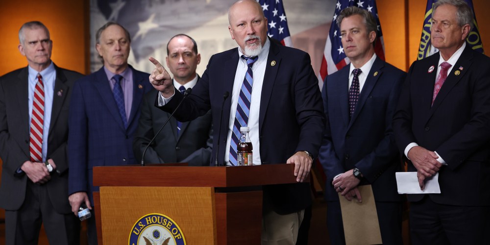 Chip Roy speaks in the foreground while other Freedom Caucus members stand in the background.