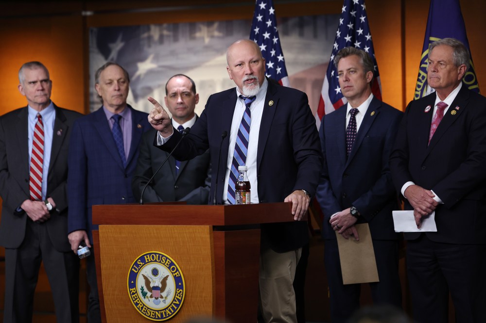 Chip Roy speaks in the foreground while other Freedom Caucus members stand in the background.